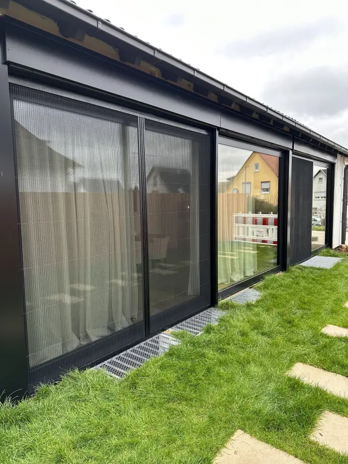 Insektenschutz-Schiebeanlage in Anthrazit an einer breiten Terrassenfront, Ansicht vom Garten